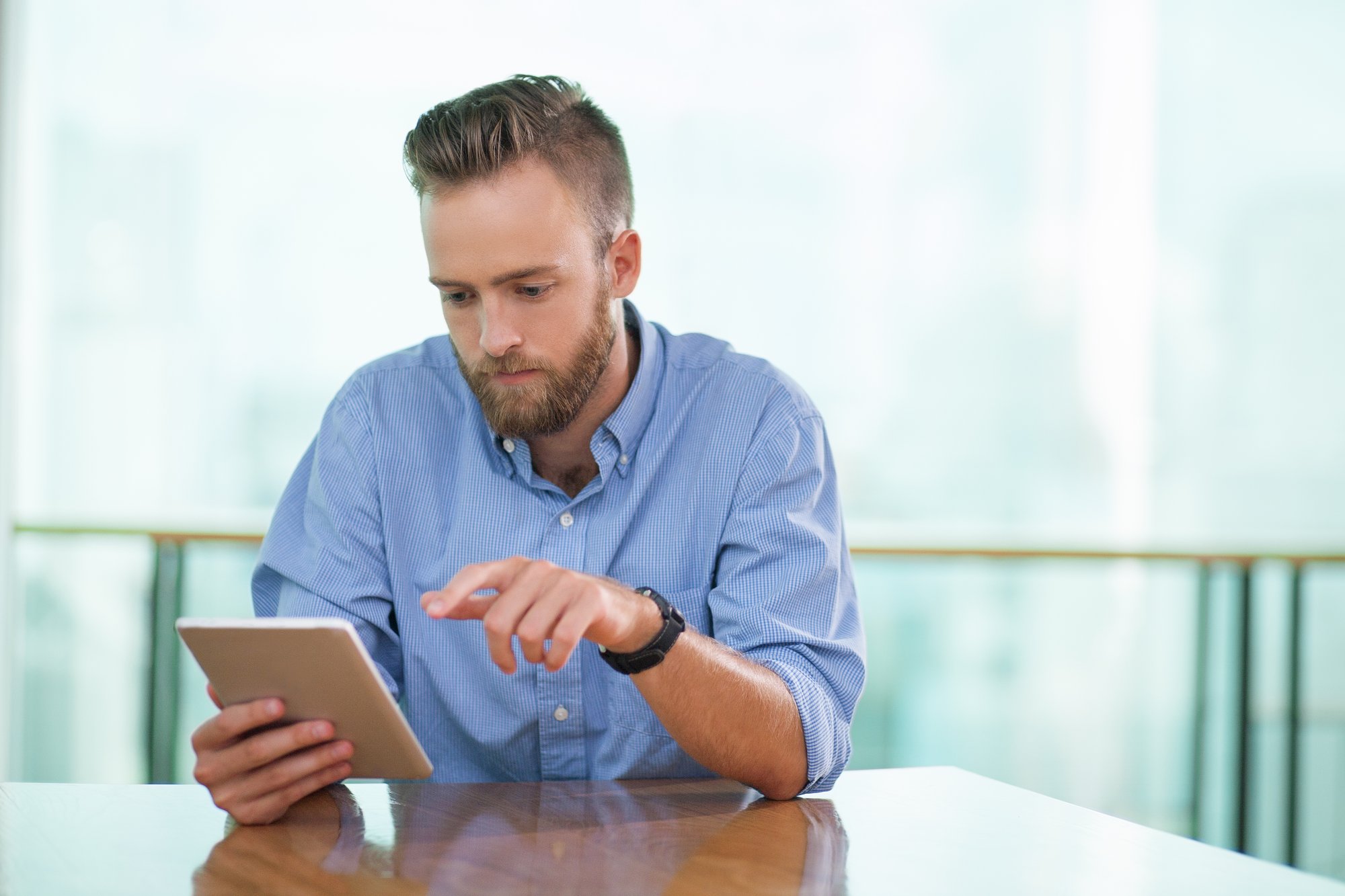 serious-man-sitting-cafe-table-using-tablet